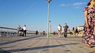 Crowded embankment on a summer day in Nizhny Novgorod. Adults, families with children walk in the summer by the river