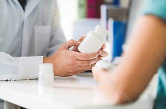 Doctor consulting patient about right medication. Physician holding medicine and pills in hand.