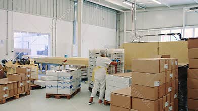 Candy factory. Factory worker pushing cart with candies in storage room.