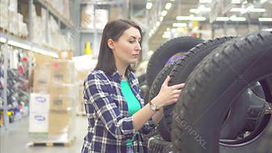 Girl in a plaid shirt buys spike winter tires in a store