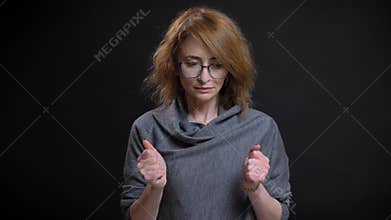 Closeup portrait of middle-aged extravagant redhead female in glasses being worried and nervous clenching her fists in