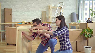 Young married couple gathers a bedside table in a new modern apartment