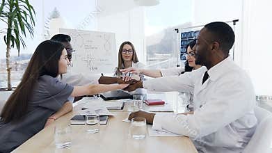 Group of five doctors putting hands together and lifting up.