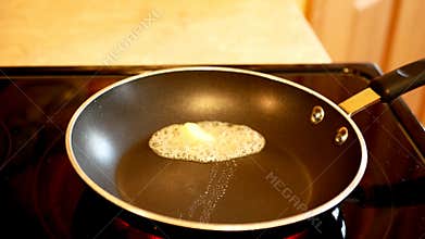 Butter melting in a hot frying pan with steam rising.