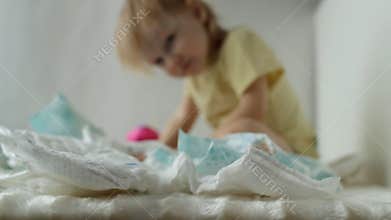 A small child plays with baby diapers, background, hygienics