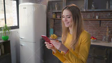 Girl use smart phone paying remote in flat.