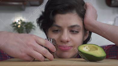 Portrait of young hungry girl choosing between fresh avocado and tasty brownie cake and after eating cake. Close up.