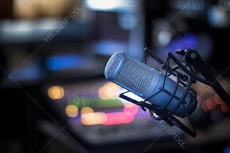 Microphone in a professional recording or radio studio, equipment in the blurry background