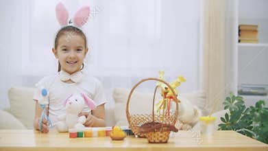 Little cute and adorable girl is smiling and playing with Easter bunnies in her hands. Concept Easter holiday.
