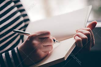 Woman writing diary by the window