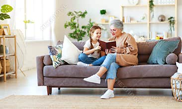 Happy family grandmother reading to granddaughter book at home