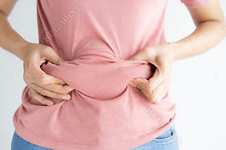 Woman hand holding her own belly fat and cellulite on white background. Women before weight loss and shape up healthy stomach