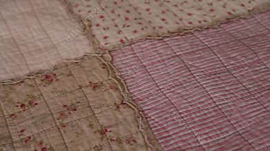 Camera moves along beige patchwork quilt closeup. handicraft concept