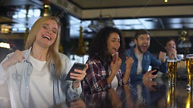 Young people in bar celebrating win in sports betting, bookmaker mobile app