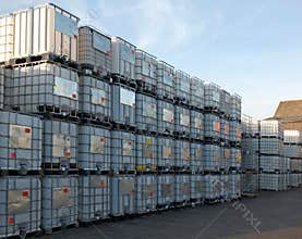 Used metal framed intermediate bulk containers stacked on pallets waiting to be cleaned or recycled in an industrial yard