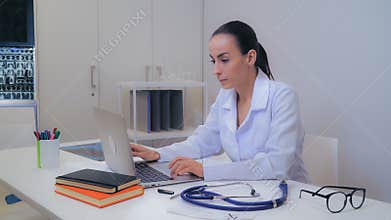 Doctor entering data on laptop.