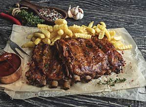 Grilled pork ribs with sauce on a cutting board, french fries