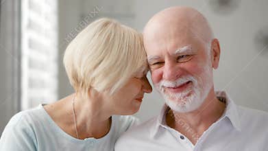 Portrait of happy senior couple at home. Senior man expresses his emotions and kisses his wife