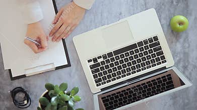 Young woman working with laptop and writing on paper idea, sitting at table, whis green apple.