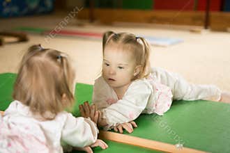 Girl with Down syndrome looks at his reflection in the mirror