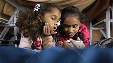 Smiling preschool girls browsing web on smartphone