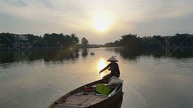 Man Sits in Boat Holding Fishing Nets against Sunrise