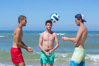 Fitness men playing volley ball at beach