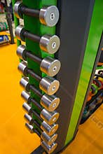 Dumbbells in gym, close up many on horizontal rack in sport fitness centre.