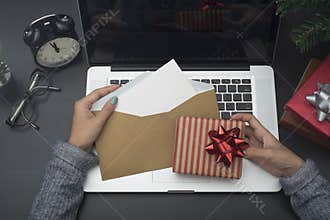 Business woman hand holding christmas card and gift box on desk.