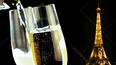 Champagne flutes with golden bubbles on golden glitter sparkle eiffel tower on black night background, holiday christmas