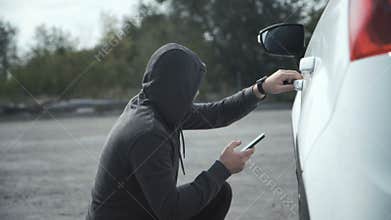 Thief breaking in car using mobile phone