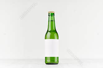 Green longneck beer bottle 330ml with blank white label on white wooden board, mock up.