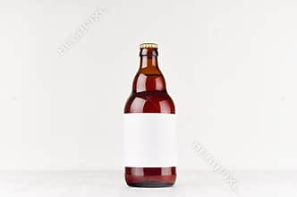 Brown belgian steinie beer bottle 500ml with blank white label on white wooden board, mock up.