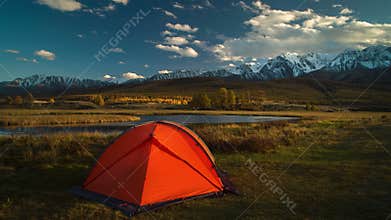 Tourist tent in camp among alpine meadows in the mountains at sunset.