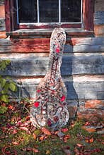 Artistic Cement Guitar Leaning against Log Home