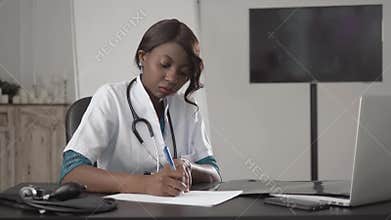 Medicine, people and healthcare concept - happy female african american doctor or nurse writing medical report to