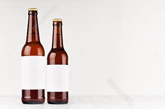 Brown beer bottles longneck 500ml and 330ml with blank white label on white wooden board, mock up.