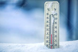 Thermometer on snow shows low temperatures - zero. Low temperatures in degrees Celsius and fahrenheit. Cold winter weather - zero.