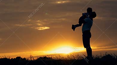 Silhouette of happy family father of mother and two sons playing outdoors in field at sunset