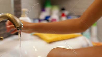 Child hands washing at the bathroom faucet