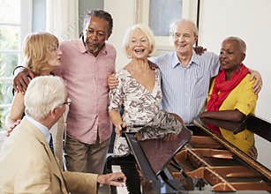 Group Of Seniors Standing By Piano And Singing Together