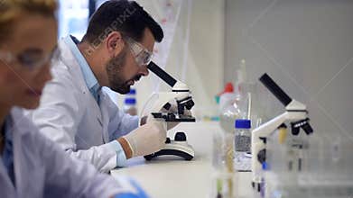 Male researcher looking through microscope in lab
