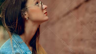 Lovely young blonde woman with red lips posing at the brick wall
