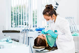 Female dentist checking up patient teeth with braces at dental clinic office. Medicine, dentistry concept. Dental