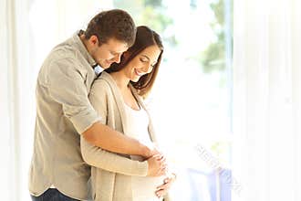 New parents looking at belly of pregnant mother