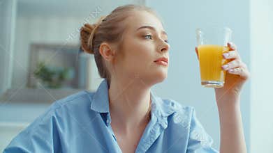 Portrait of happy young woman drinking orange juice during breakfast.