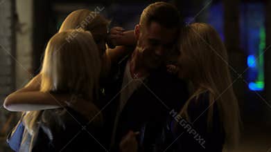 Three beautiful blond women flirting with man at night club, relaxation, hook-up