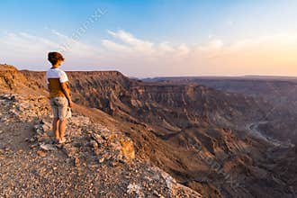 One person looking at the Fish River Canyon, scenic travel destination in Southern Namibia. Expansive view at sunset. Wanderlust t