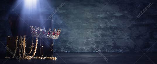 Image of mysterious opened old wooden treasure chest with light and queen/king crown with red Rubies stones. fantasy medieval peri