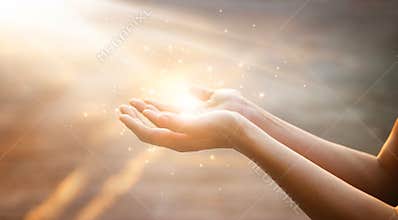 Woman hands praying on sunset background